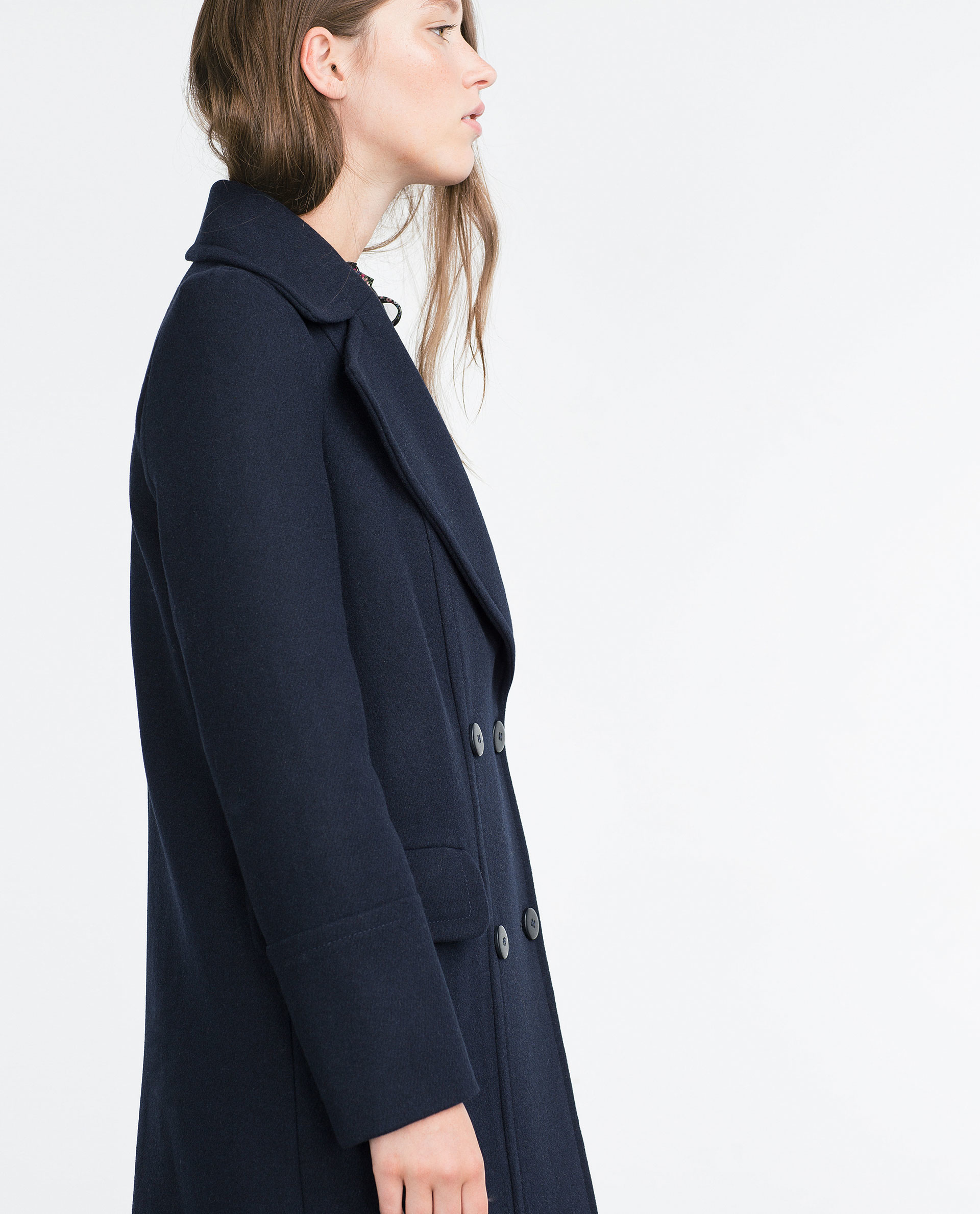 Long navy blue coat This stunning long wool coat for womens is beautifully fitted and tailored for a classic, feminine design. It features navy blue, a slim fitting bodice with elongated sleeves and tapered waist band leading into a long, flowing skirt, shoulders and sleeve cuffs have a pretty ruffle detailing.